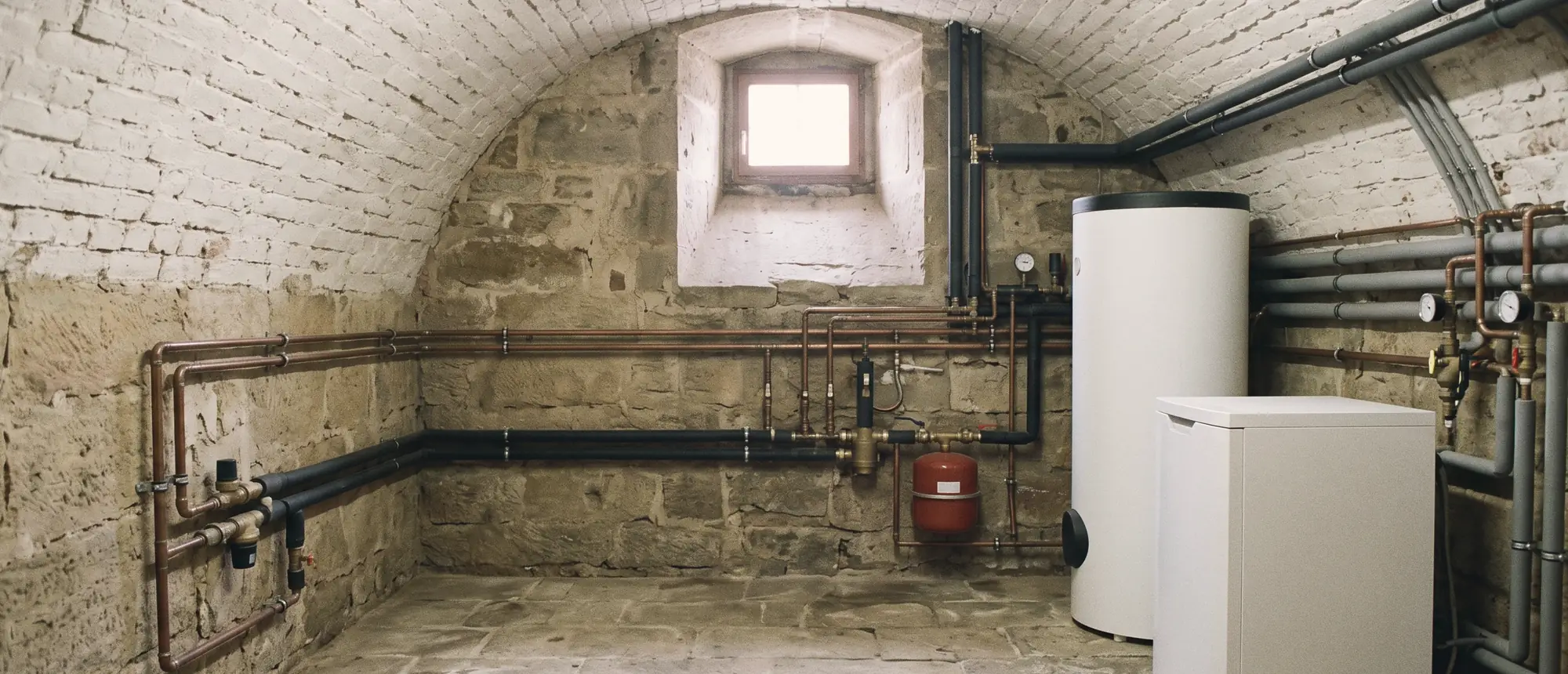 Gewölbekeller mit neu installierter Wärmepumpe, Speicher und sauber geführten Leitungen