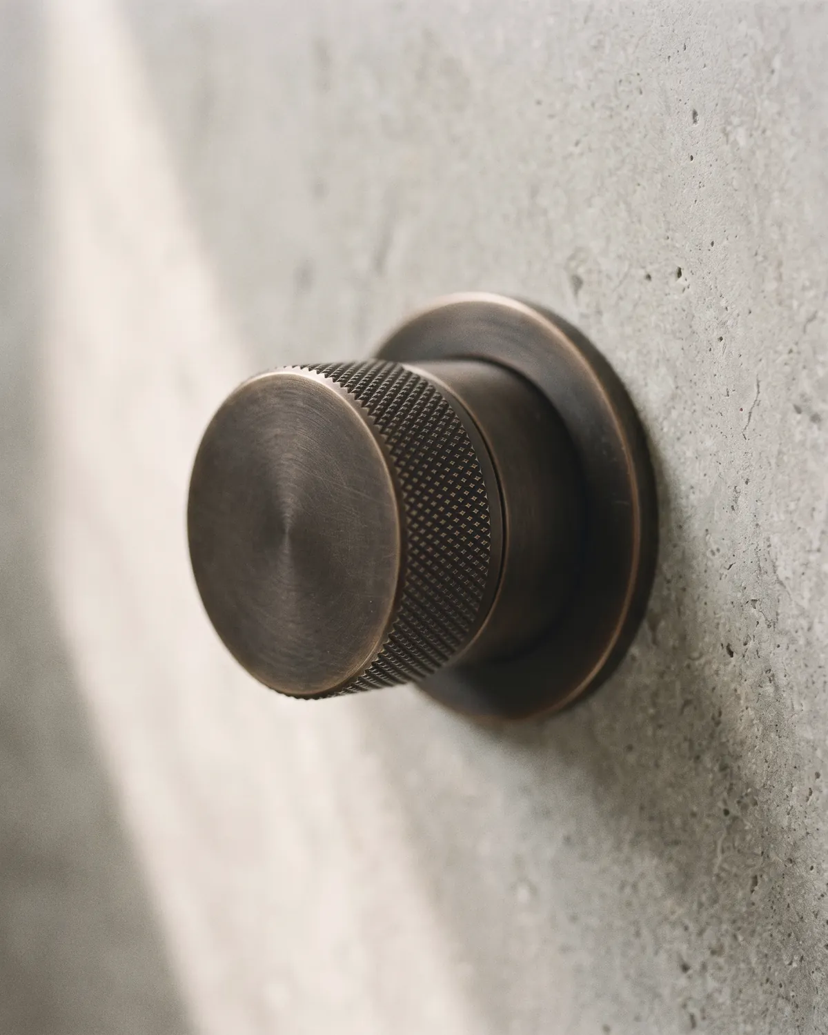 Thermostatgriff aus dunkler Bronze an einer Steinwand